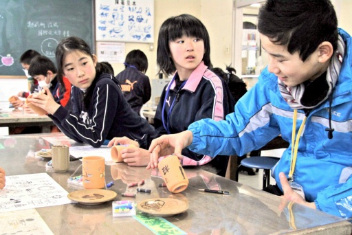 越前焼の湯飲みに絵付けし交流する児童たち＝４日、福井県越前町の県陶芸館