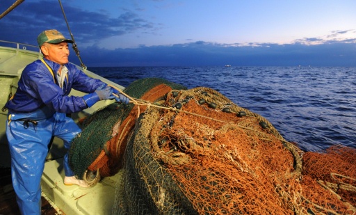 【夜明け前】周囲の海がうっすらと明るくなる中、次の網の仕掛けを準備をする漁師＝６日午前６時５分ごろ