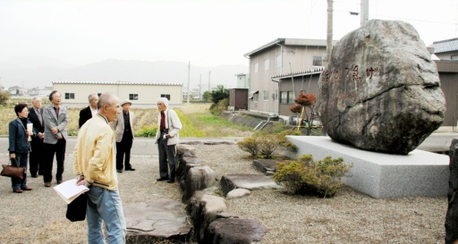 開高健の石碑を見学する「記念会福井」の会員ら＝１３日、坂井市丸岡町