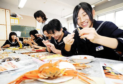 セイコガニをほぐし、笑顔で食べる生徒たち＝１０日、福井県福井市進明中