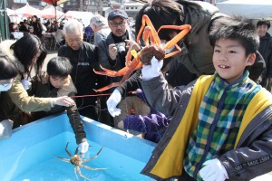 「活かに釣り大会」で大きなカニを釣り上げ、喜ぶ子ども＝１５日、越前町厨の厨漁港広場
